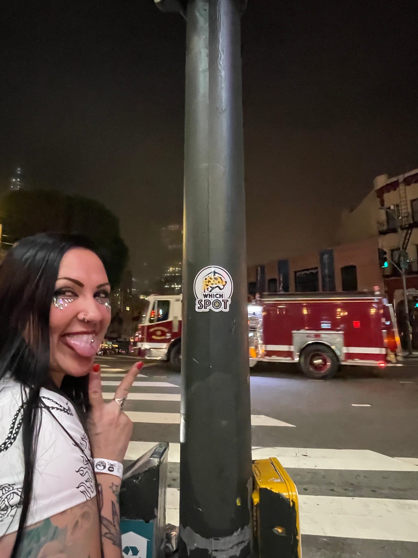 A WhichSpot co-founder pointing at the very first WhichSpot sticker on a San Francisco street pole at night, October 29, 2021